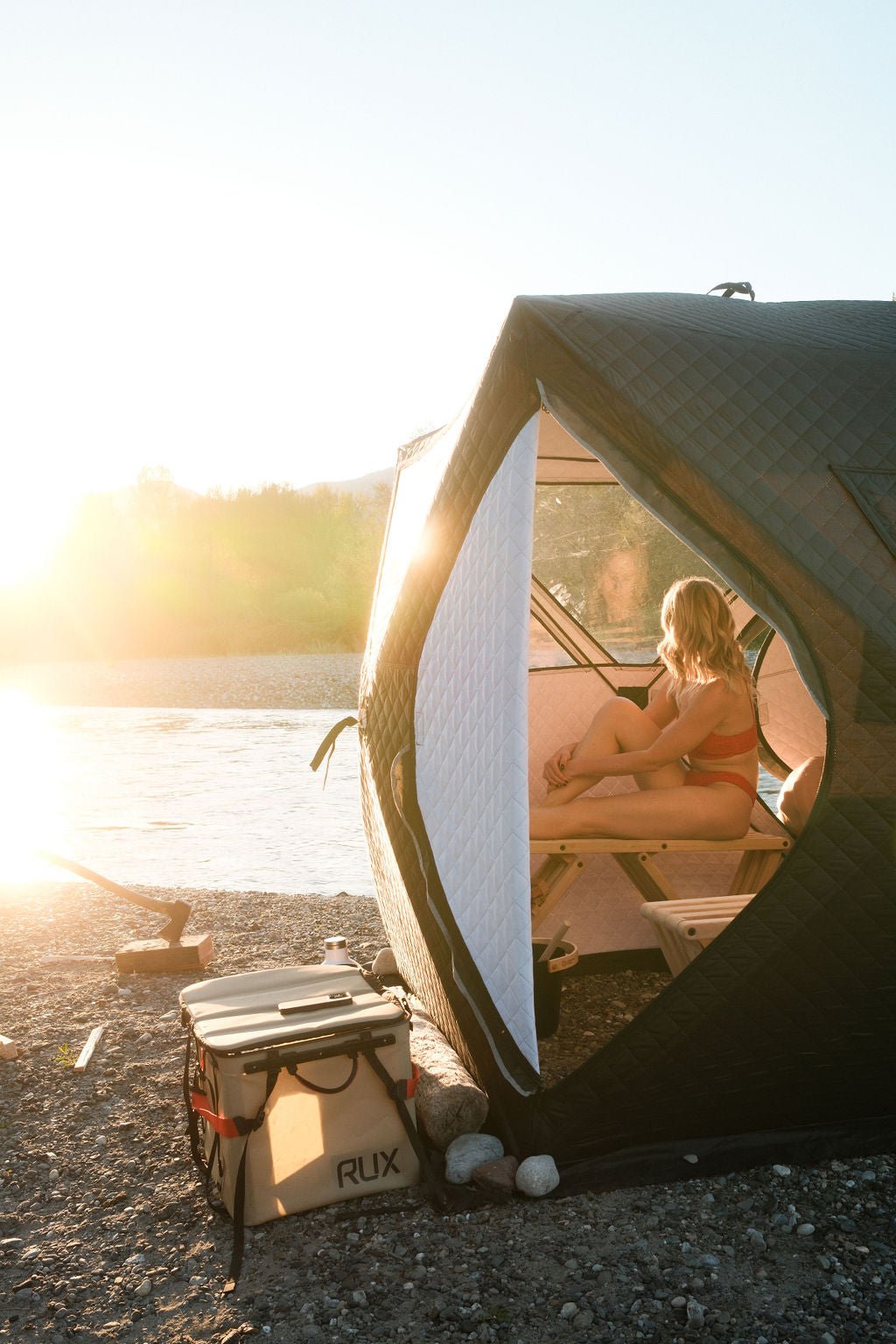 Relaxing inside the sauna tent at golden hour beside the river